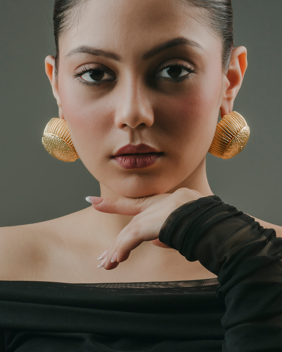 Close-up of chunky gold-toned brass statement earrings handcrafted by Indian artisans.