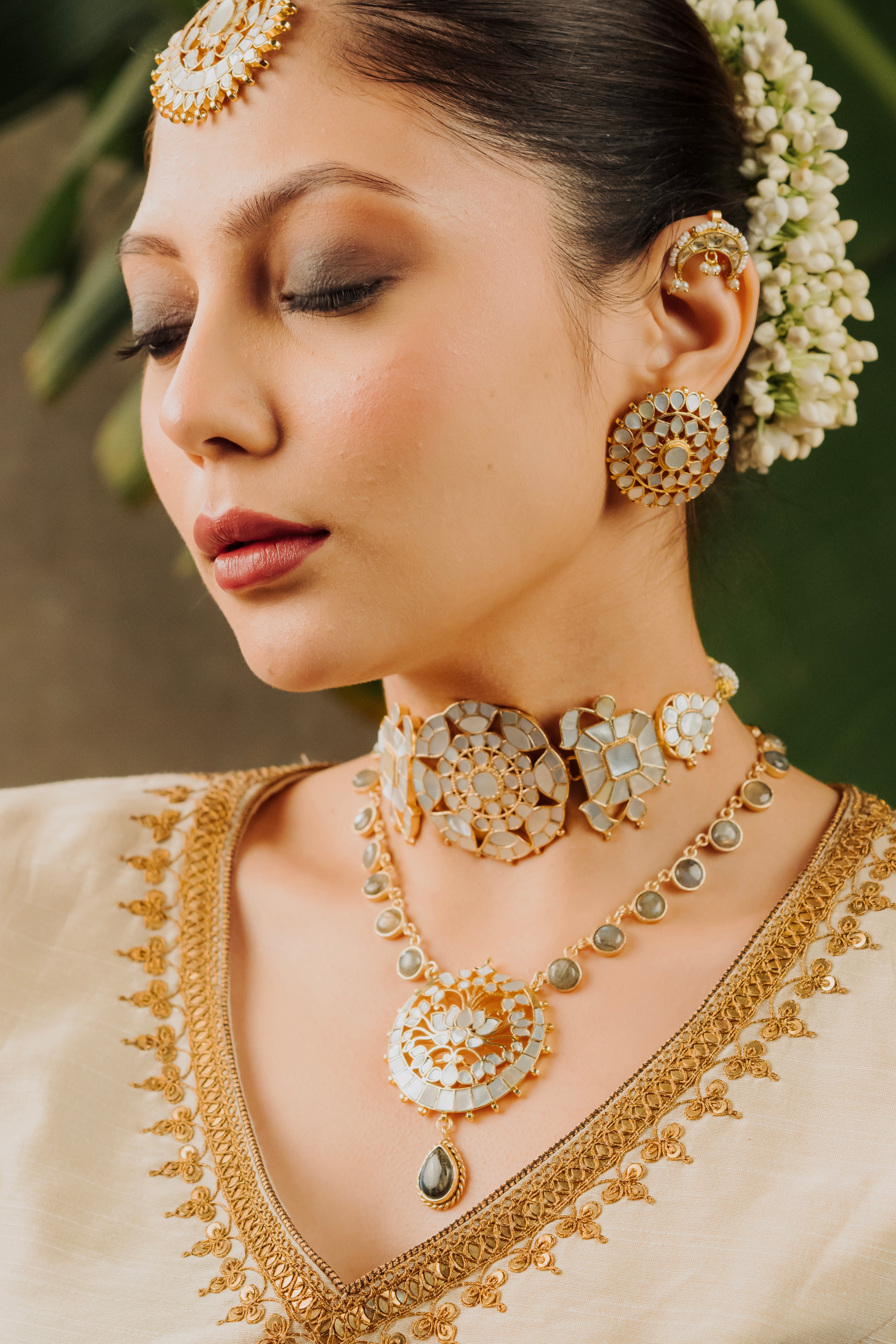 Model wearing traditional Mother of Pearl floral choker set styled with a teal blue ethnic saree for wedding festivities.
