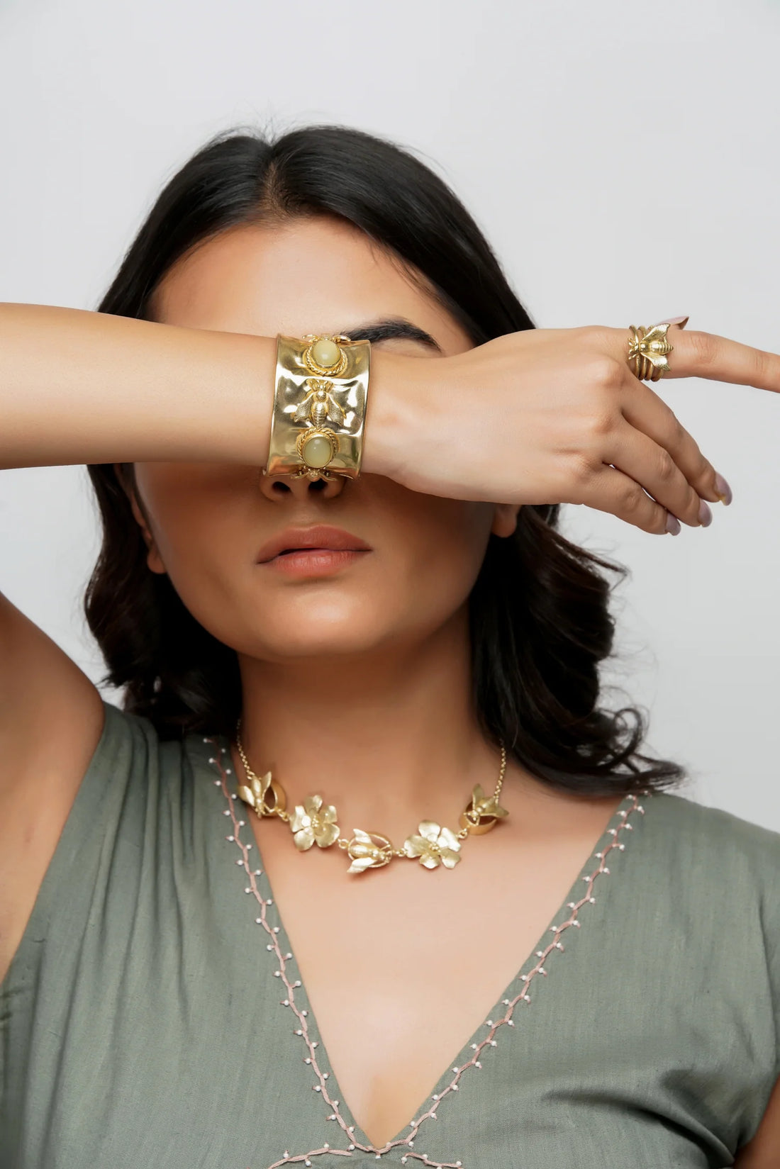 a girl wearing statement bracelet with stylist floral necklae along with bees motif ring