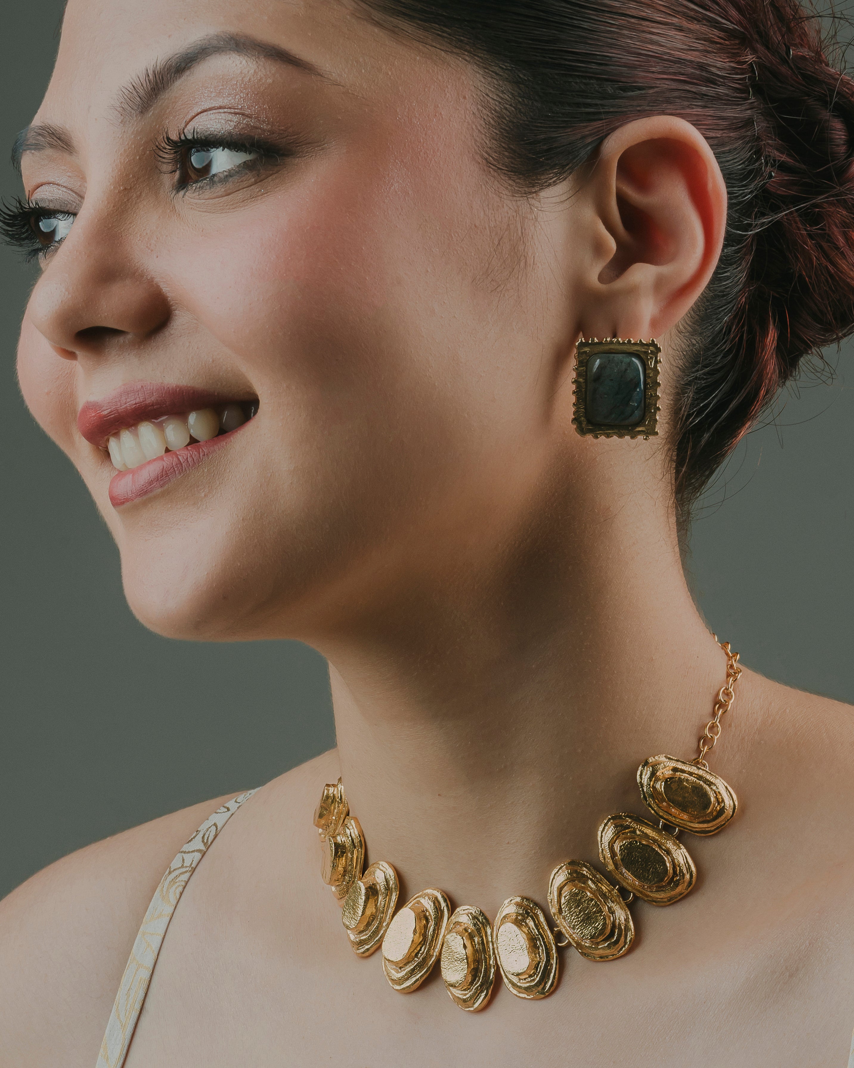 woman showcasing Lebra handcrafted statement stud earrings paired with a matching gold necklace.