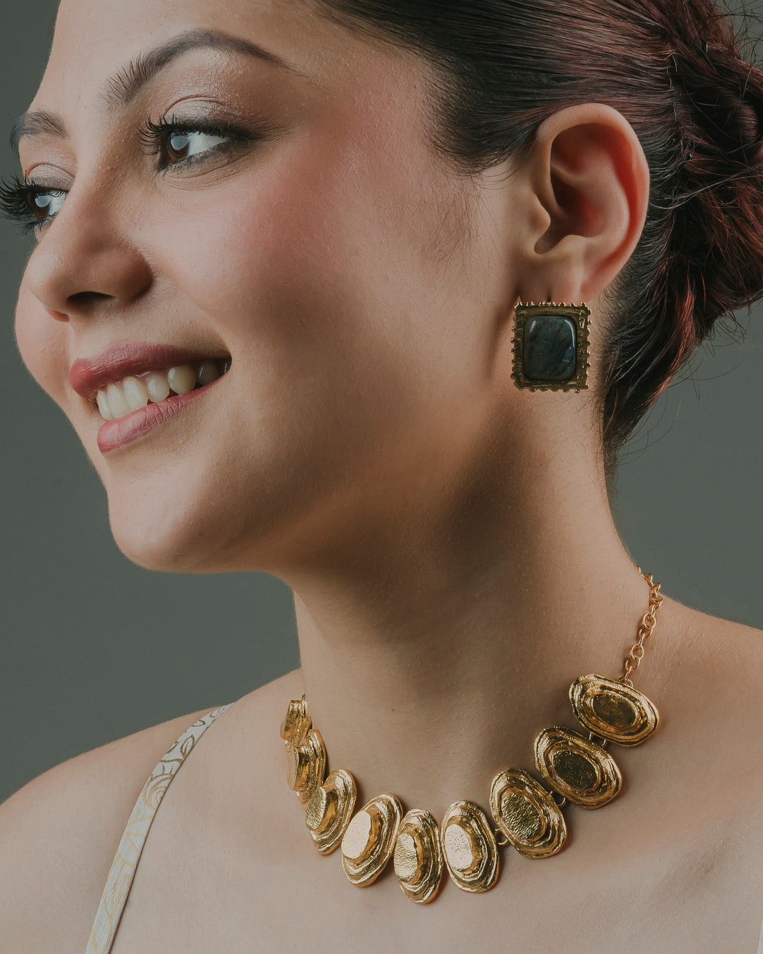 woman showcasing Lebra handcrafted statement stud earrings paired with a matching gold necklace.