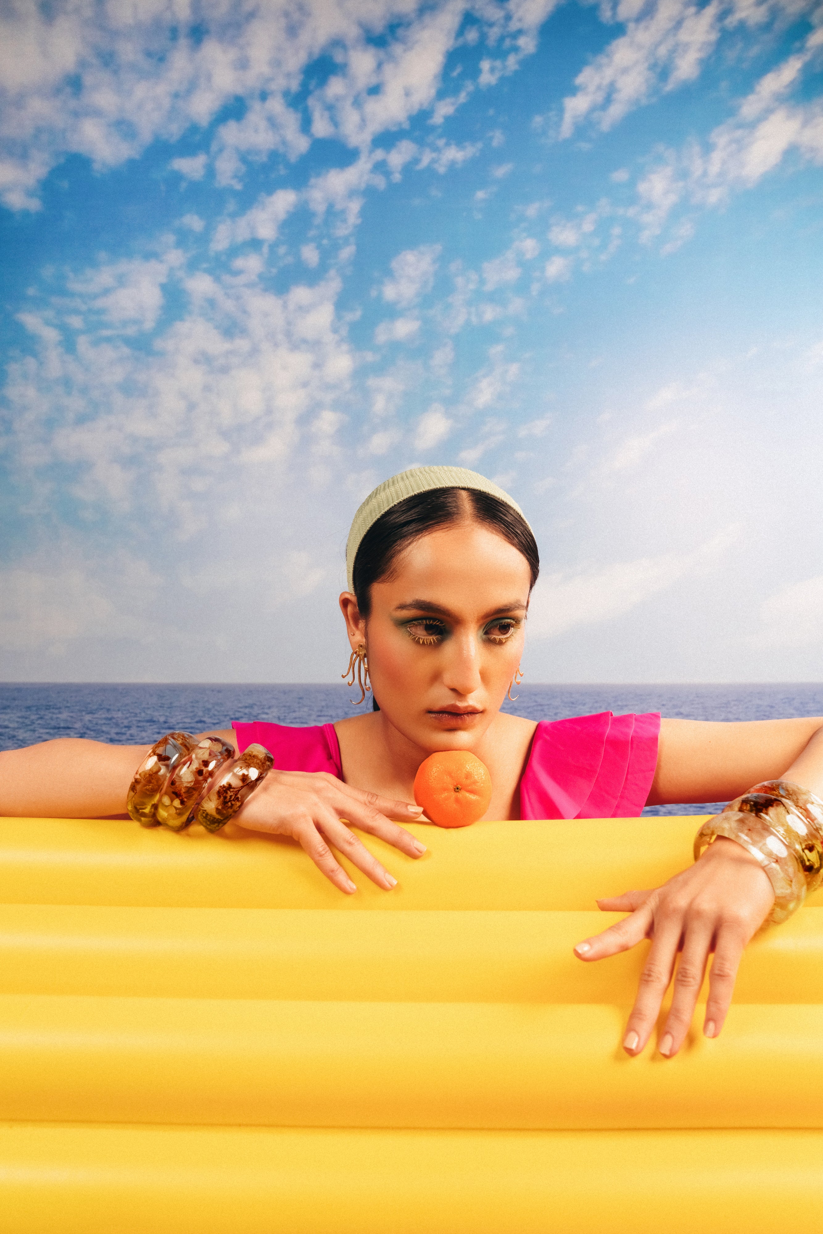 Women's gold-plated octopus resort earrings styled with bright pink summer outfit.