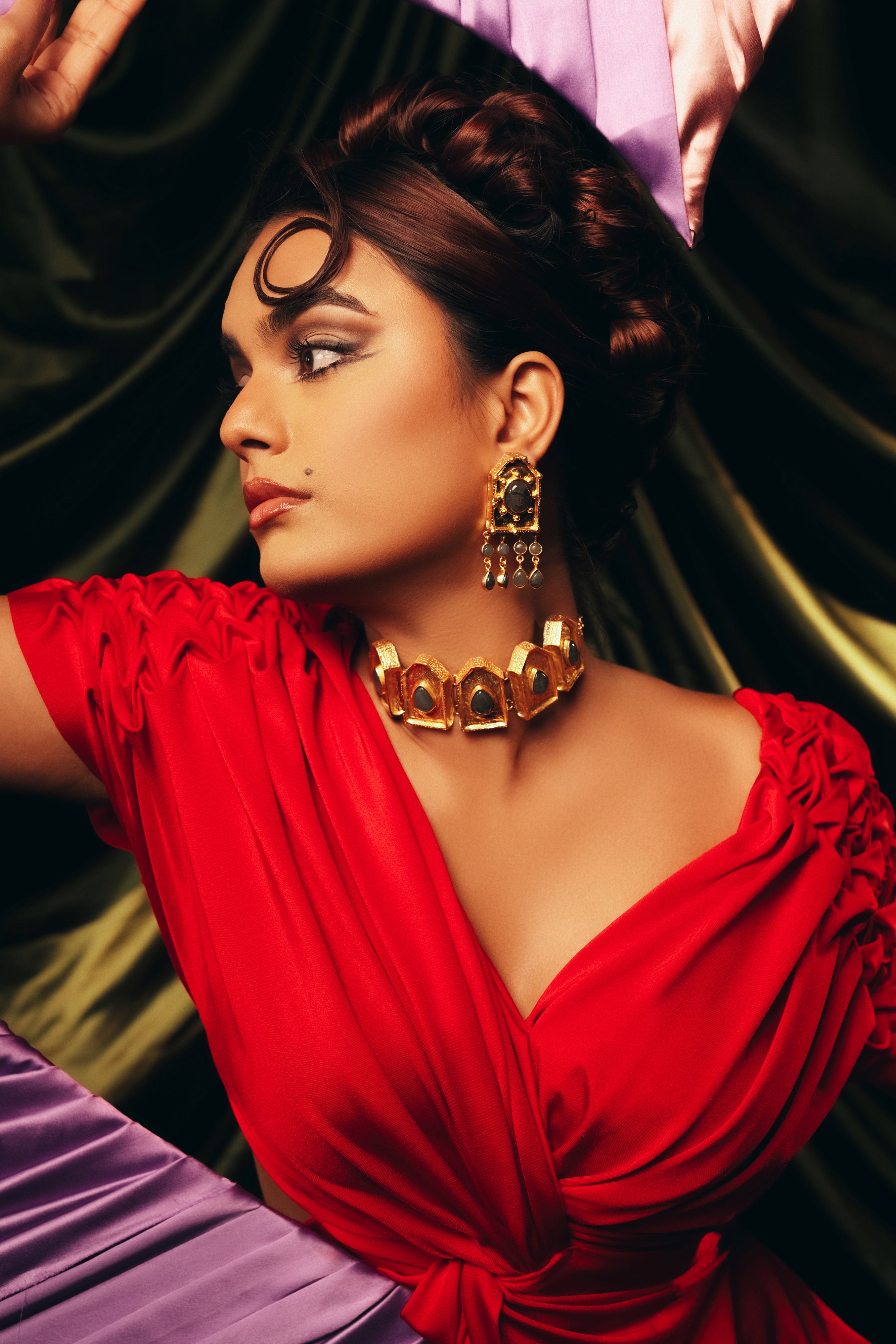 Woman wearing statement ruby zoisite dangle earrings with gold ball accents and asymmetrical design