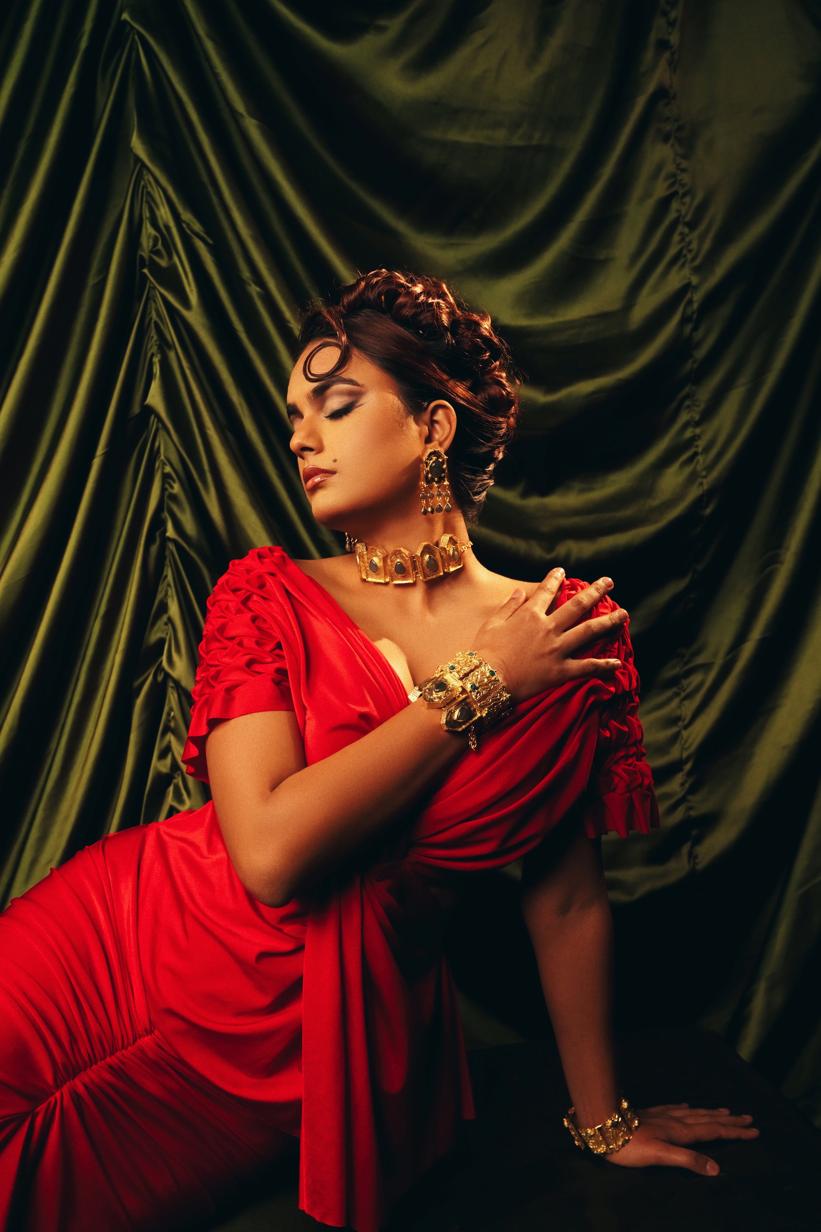 Model styled in a traditional red saree featuring a bold gold statement choker necklace.