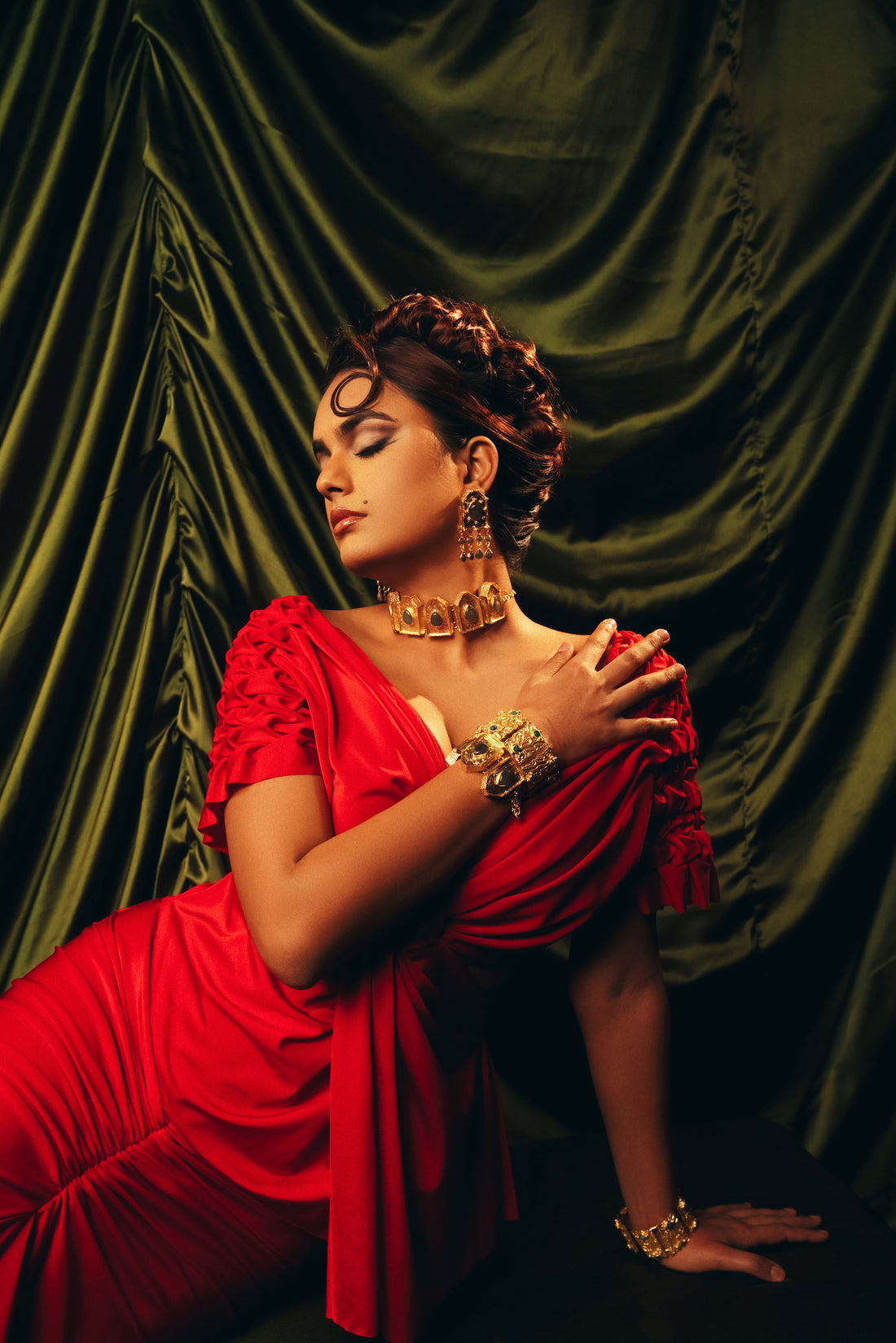 Model styled in a traditional red saree featuring a bold gold statement choker necklace.