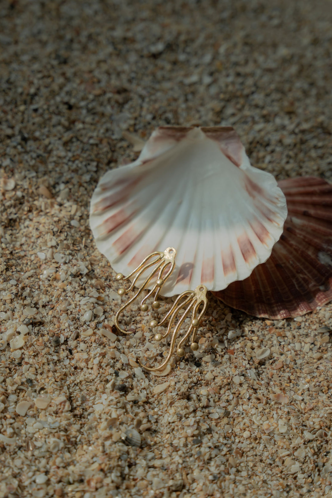 Unique ocean-themed gold octopus drop earrings worn with matching gold cuffs for summer